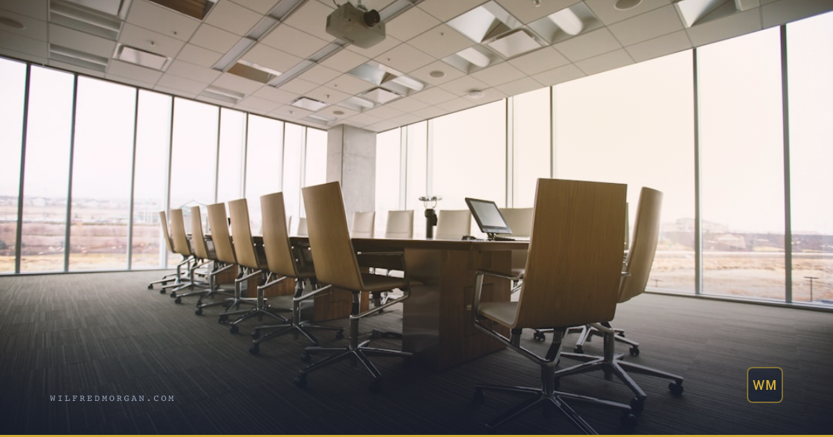 Scene: An empty dark modern boardroom with a long conference table
